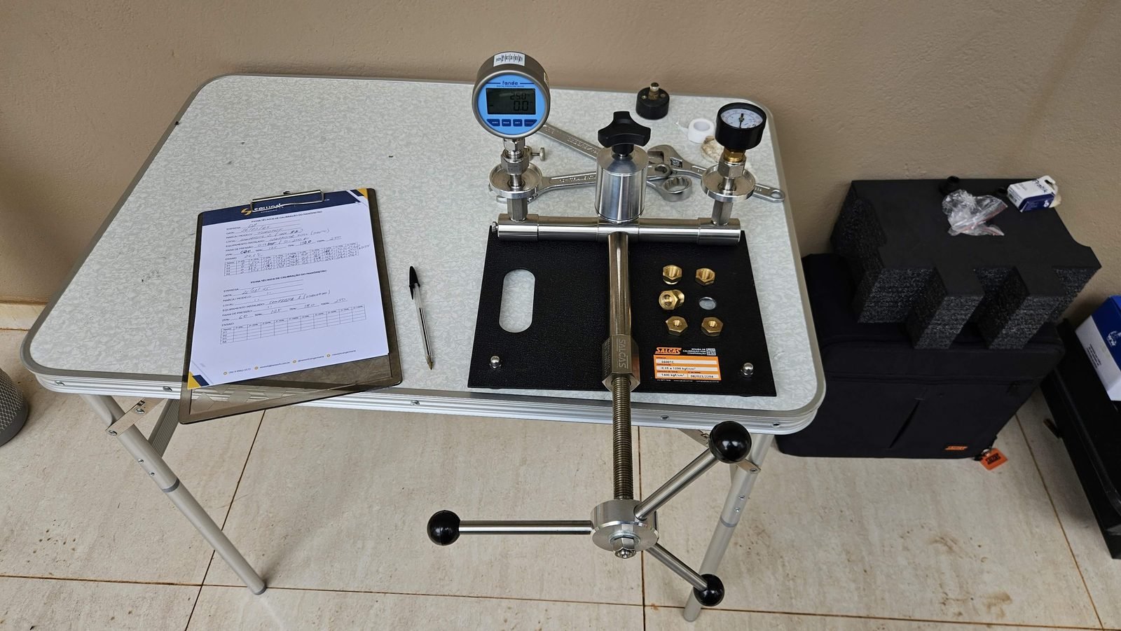 Bancada de calibração de manômetro com bomba comparadora e padrão digital, usada na aferição de instrumentos de vasos de pressão