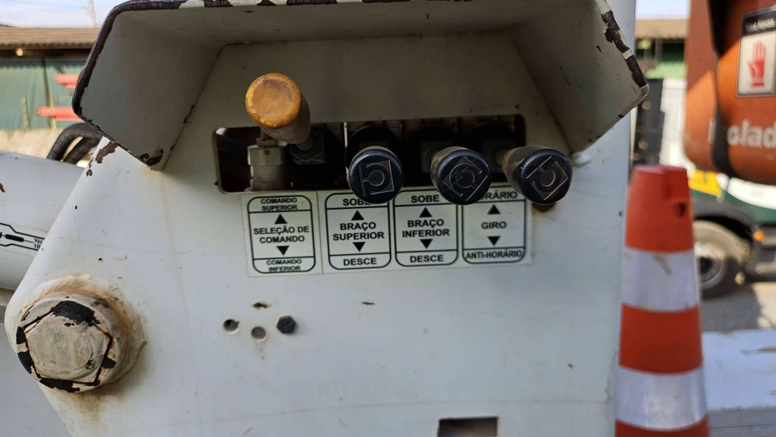 Painel de comandos inferior de cesto aéreo com identificação legível de seleção de comando, braço superior, braço inferior e giro