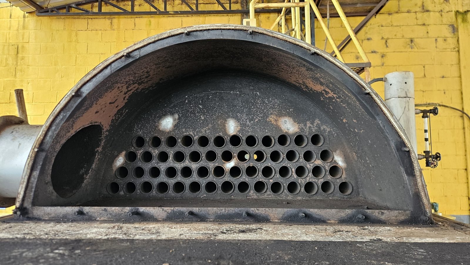Porta de inspeção de caldeira aberta expondo o feixe tubular para exame interno