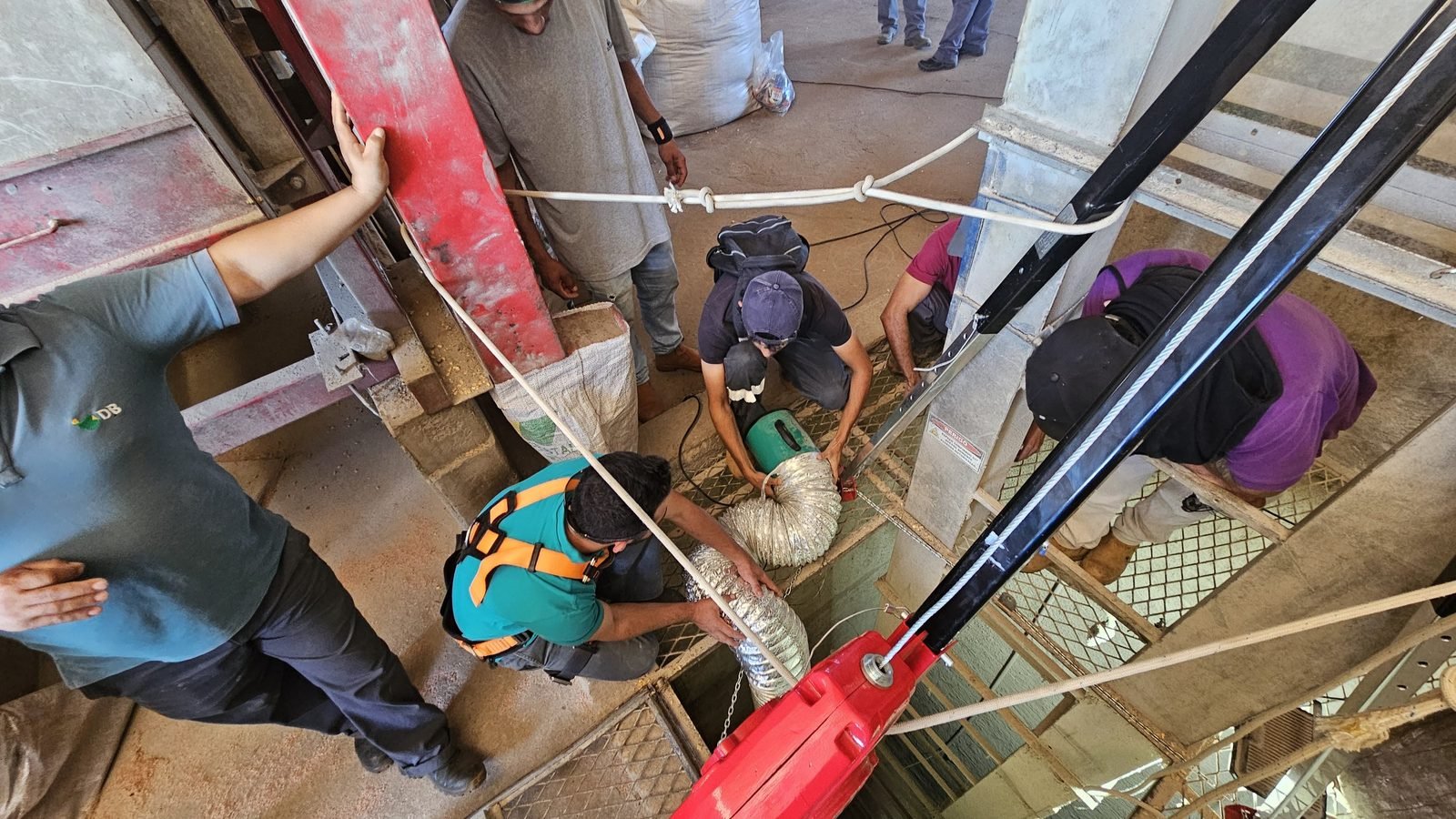 Equipe em treinamento de espaço confinado NR-33 com tripé de resgate e ventilação forçada